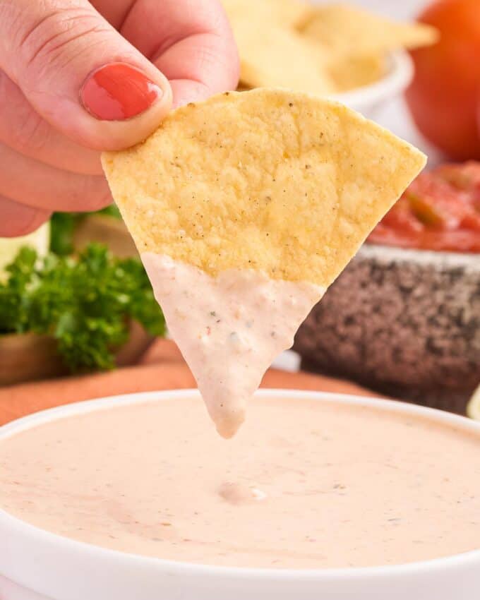 dipping a tortilla chip into a bowl of salsa ranch.