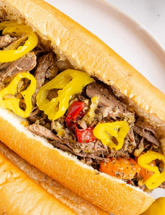 Deliciously tangy and piquant, this slow cooker Italian beef is made easily with simple ingredients and cooks all day, so it's ready when you get home! Perfect on sandwiches, sliders, or over mashed potatoes, this recipe is pure comfort food.