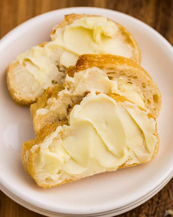 three slices of bread smeared with butter on a plate.