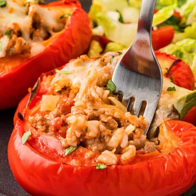 digging a fork into a sausage stuffed pepper.
