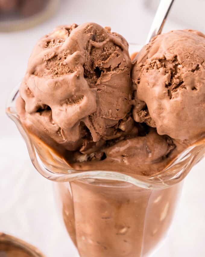 scoops of chocolate malt ice cream in a sundae glass with a spoon.