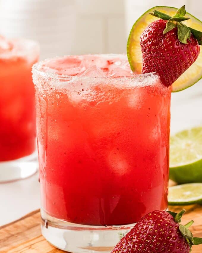 strawberry margaritas garnished with a sugar rim, strawberry, and lime slice.