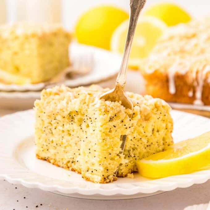 fork slicing a piece of a slice of lemon poppyseed coffee cake.