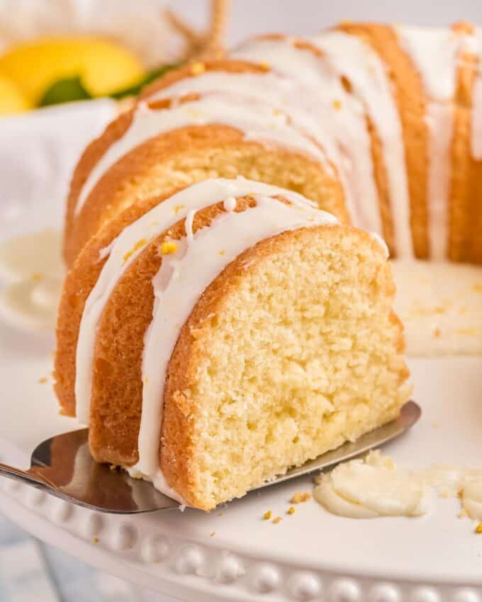 removing a slice of lemon bundt cake with a spatula.