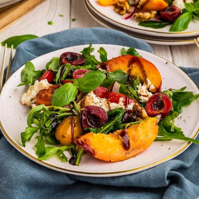 burrata salad with peaches and balsamic glaze on a white plate.