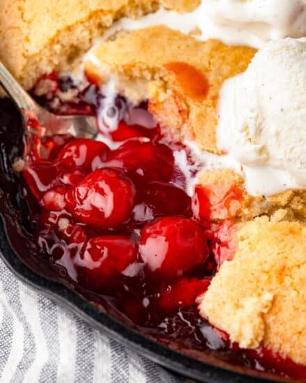 This mouthwatering cherry cobbler is made with canned cherry pie filling (for convenience) and a simple cake batter. As the cobbler is baked, the batter bakes up into a cobbler-style crust on top of the sweet cherries. This recipe is extremely versatile, so you can use homemade pie filling instead of canned, or switch up and use a different fruit filling!