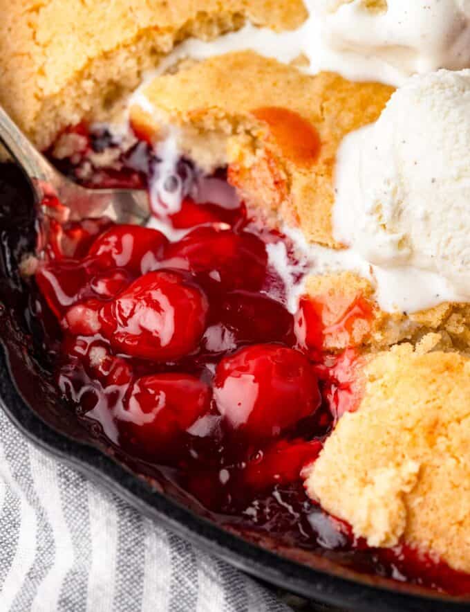 This mouthwatering cherry cobbler is made with canned cherry pie filling (for convenience) and a simple cake batter. As the cobbler is baked, the batter bakes up into a cobbler-style crust on top of the sweet cherries. This recipe is extremely versatile, so you can use homemade pie filling instead of canned, or switch up and use a different fruit filling!