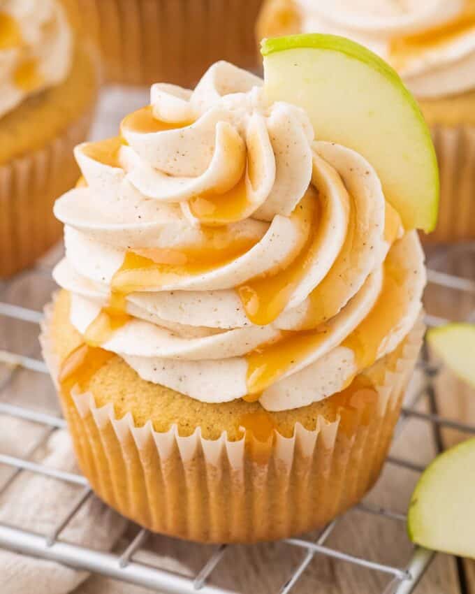 caramel apple cupcakes on cooling rack, drizzled with caramel syrup.