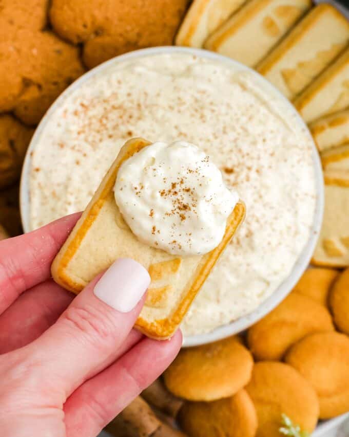 scooping eggnog dip with a shortbread cookie