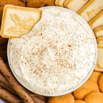 bowl of eggnog dip surrounded by cookies to dip with.