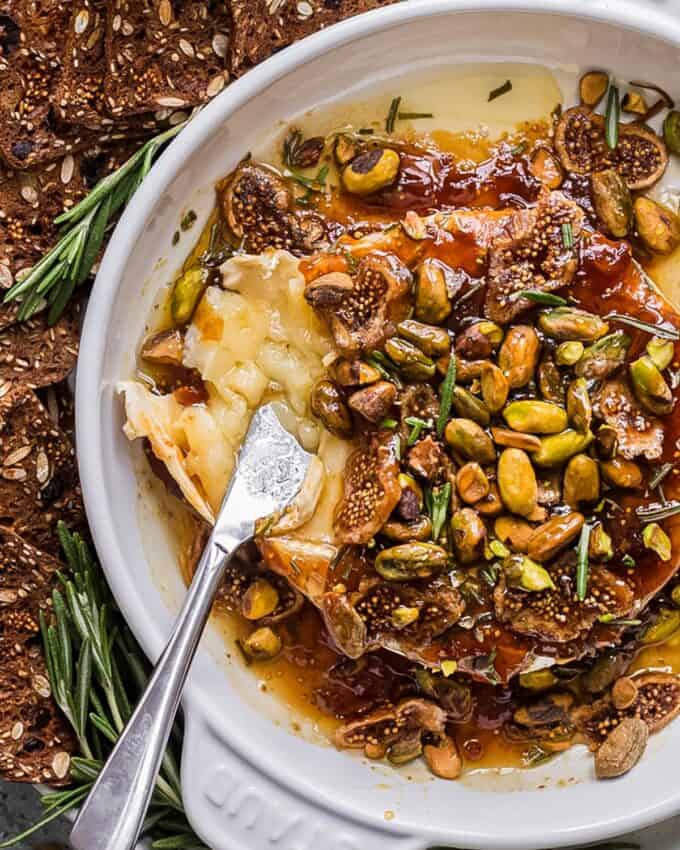 digging into baked brie with a cheese knife.