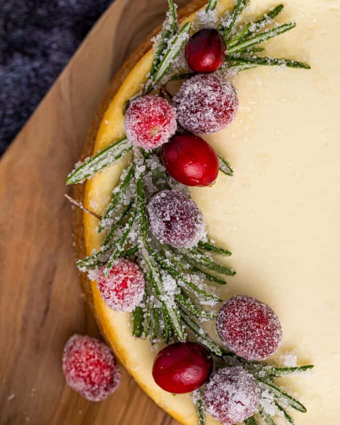 sugared cranberries and rosemary on a cheesecake.