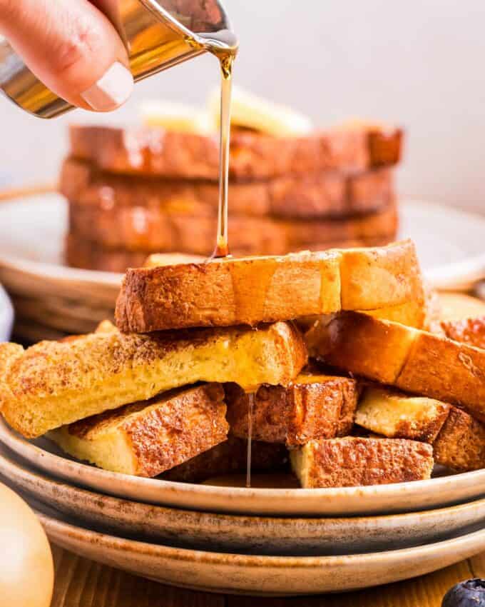 pile of french toast with syrup being drizzled over it.