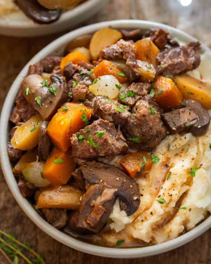 bowl of beef stew over mashed potatoes