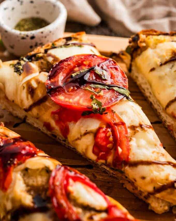 Caprese garlic bread is so simple to make! It all starts with a loaf of bakery bread that's spread with an easy homemade garlic and herb butter, then topped with fresh mozzarella, sliced tomatoes, fresh basil, and a drizzle of balsamic glaze. Perfect as a side dish, or serve with a salad or veggie to make a light meal!