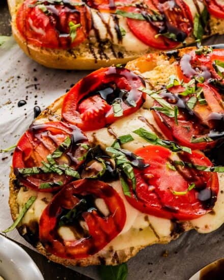 Caprese garlic bread is so simple to make! It all starts with a loaf of bakery bread that's spread with an easy homemade garlic and herb butter, then topped with fresh mozzarella, sliced tomatoes, fresh basil, and a drizzle of balsamic glaze. Perfect as a side dish, or serve with a salad or veggie to make a light meal!