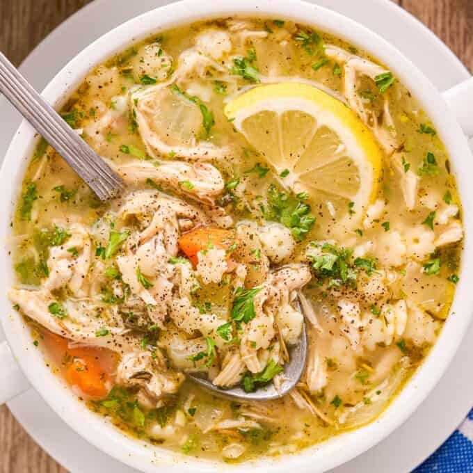 overhead photo of chicken and stars soup in a white bowl with a spoon.