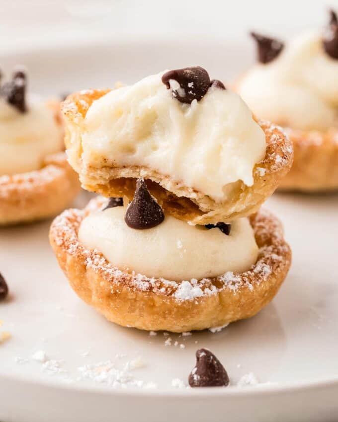 two cannoli cups stacked on top of each other, with a bite taken out of the top one.