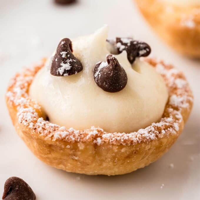 close up photo of a mini cannoli cup dusted with powdered sugar.